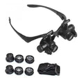 Black double eye magnifier glasses with LED lights and four sets of interchangeable lenses on a headband.