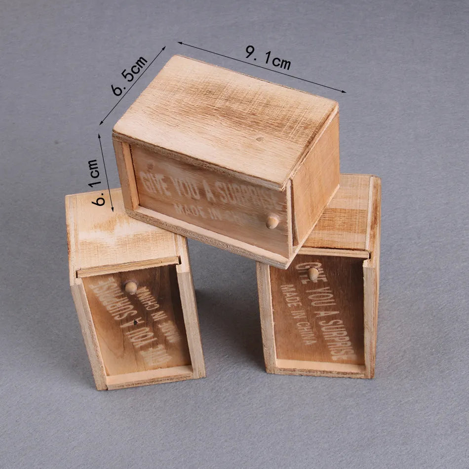 Wooden prank scare box closed, with a lifelike jumping spider toy next to it.