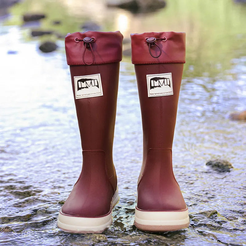 A pair of high tube PVC rain boots in a solid colour, shown on a size label with a non-slip sole.