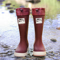 A pair of high tube PVC rain boots in a solid colour, shown on a size label with a non-slip sole.