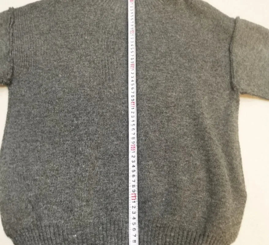 Women's dark grey acrylic sweater with side slits and matching full-length trousers laid flat.