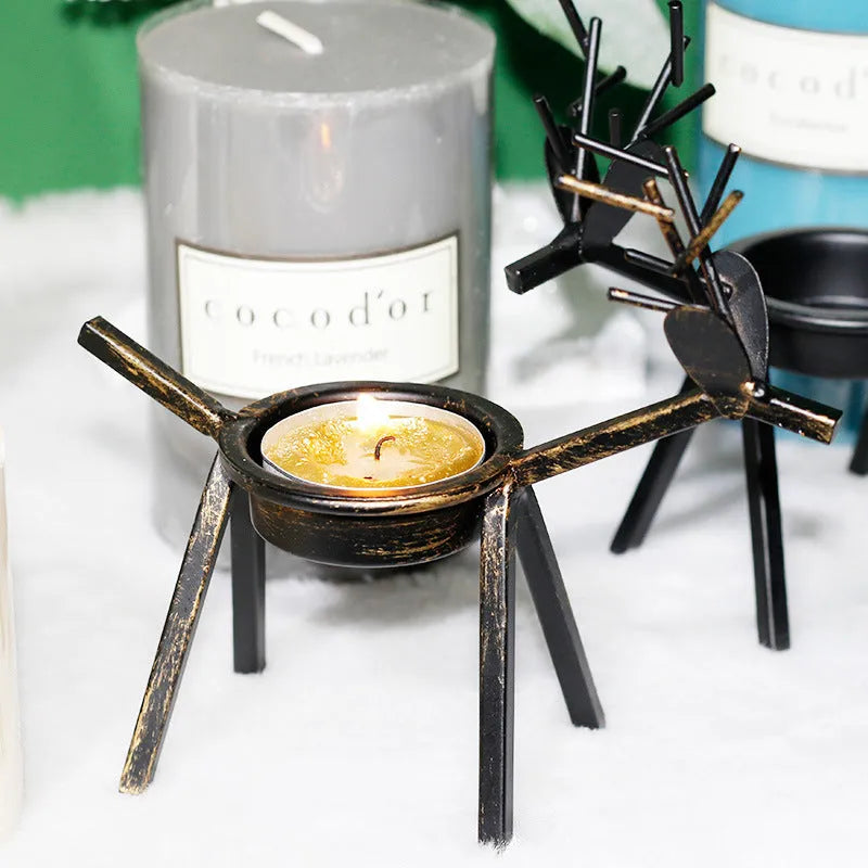 Black iron Christmas candlestick with deer and elk bracket design on a table.