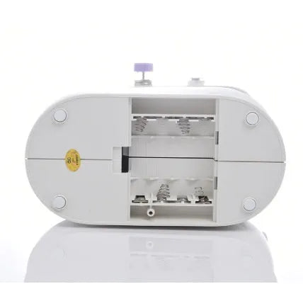 Small white plastic electric sewing machine with thread cutter and light on a table