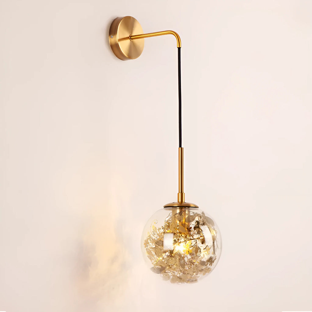 Modern small glass wall lamp in golden flower finish mounted on a bedroom wall.