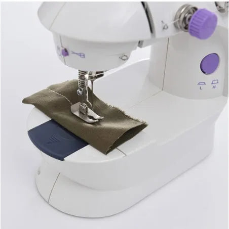Small white plastic electric sewing machine with thread cutter and light on a table