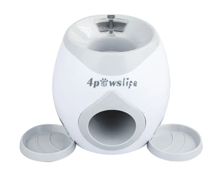 Smart pet feeder reward machine with two tennis balls and treat dispenser in green and white colour, shown on a wooden floor