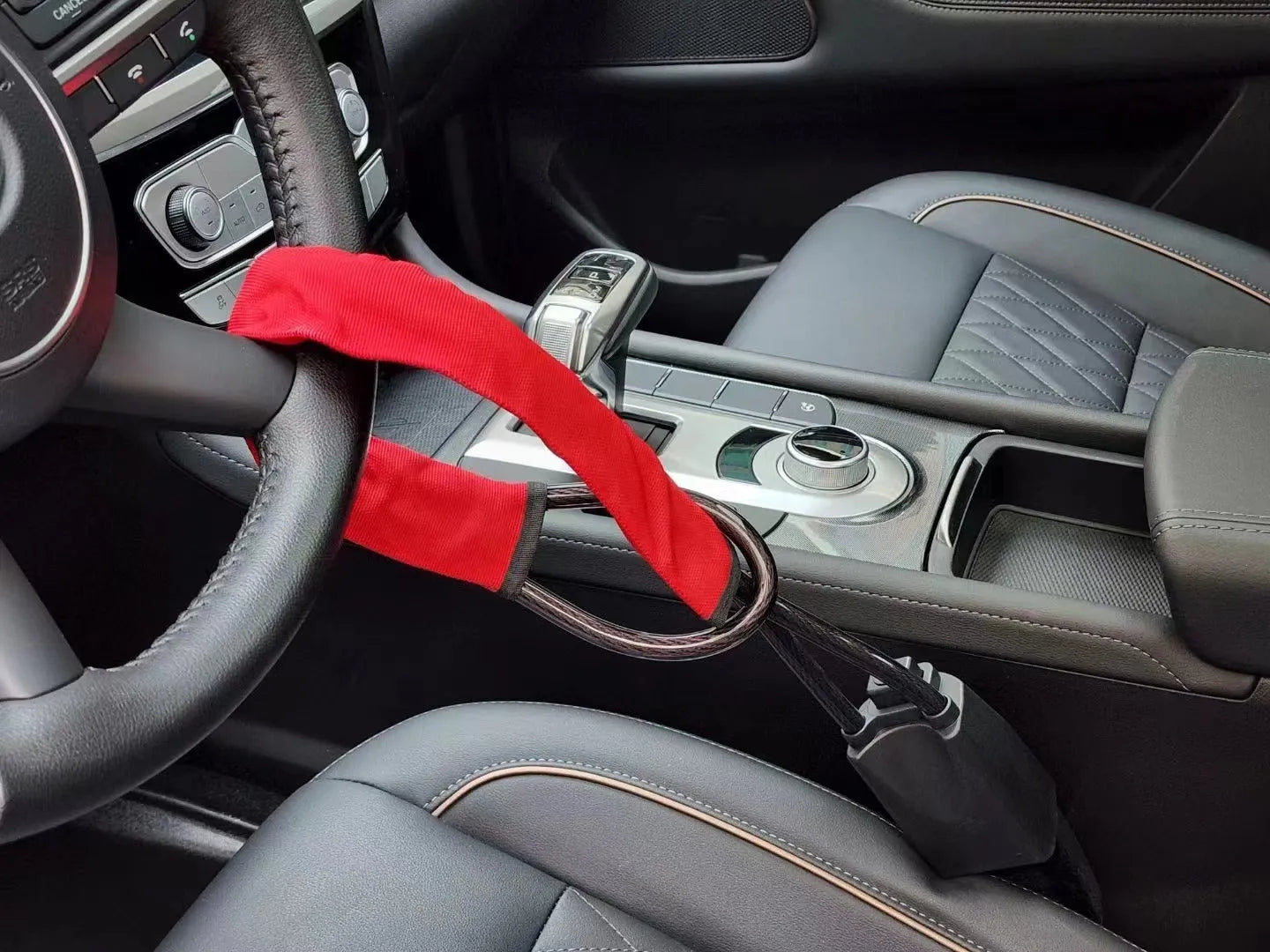 Red iron wire rope steering wheel lock for General Motors cars on a steering wheel.