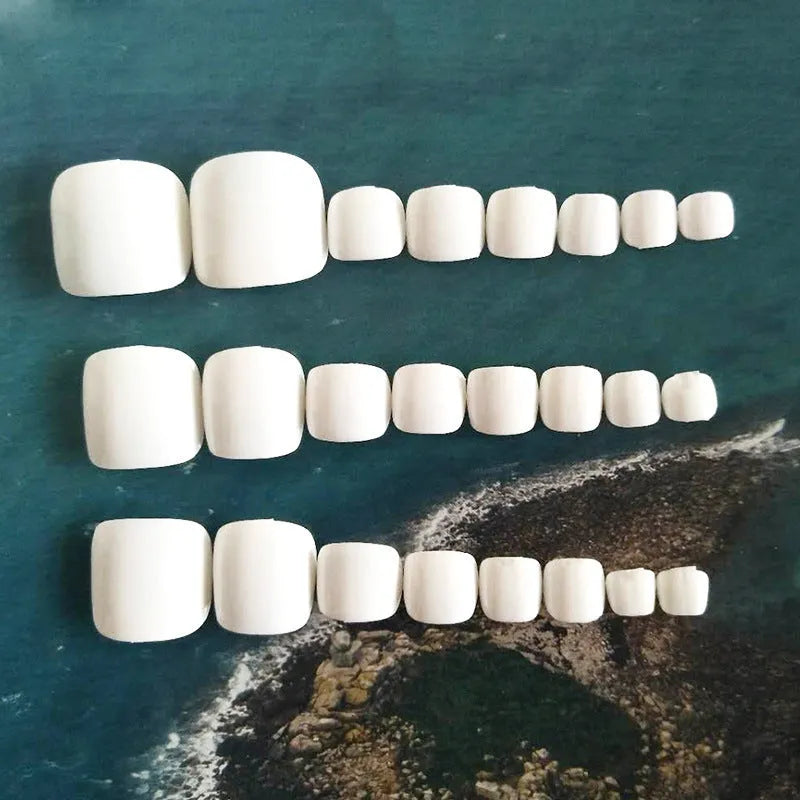 Set of white artificial false nails with a starry sky pattern, ready for application.