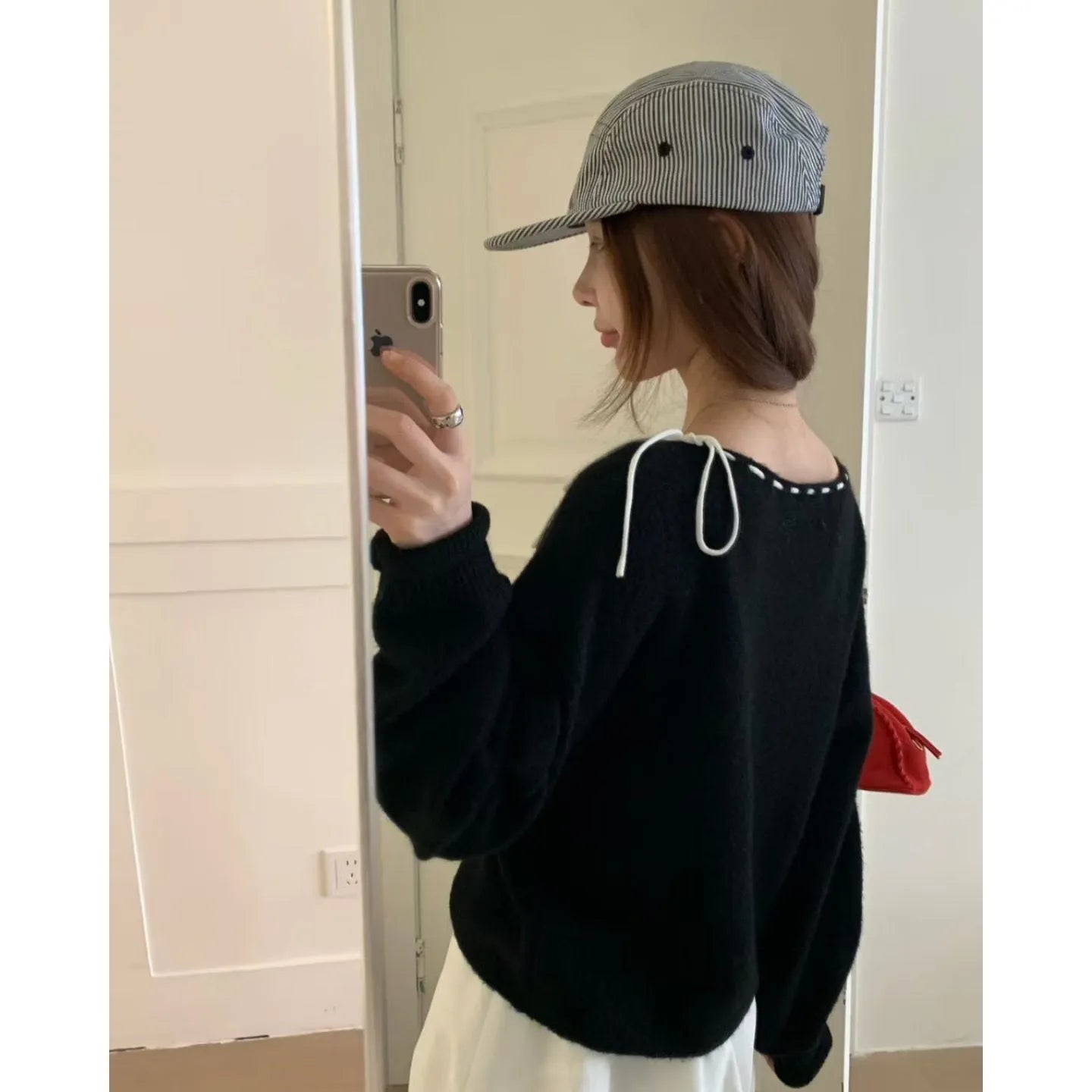 A loose-fitting black women's knitted pullover on a hanger.