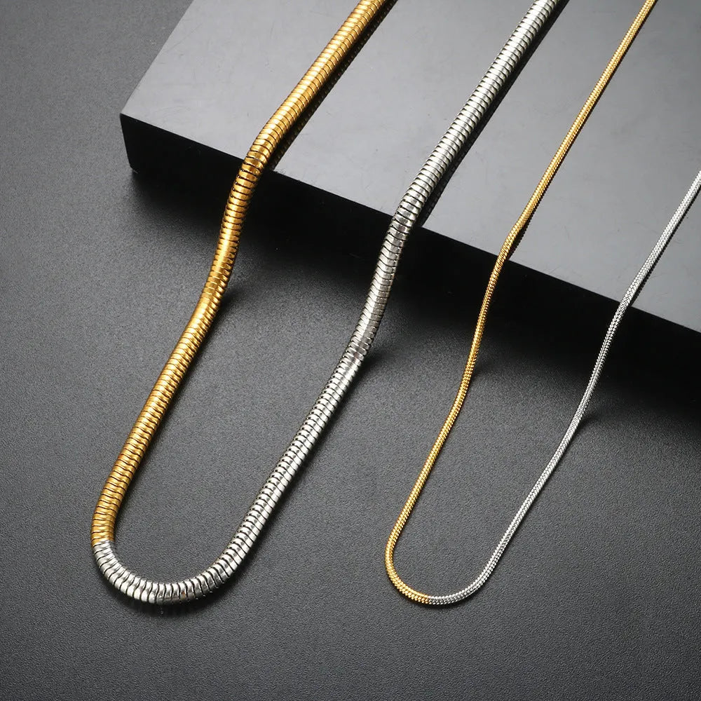 Golden stainless steel snake bone chain necklace with lobster clasp on a dark background.