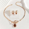 Gold alloy necklace and earrings suite with white rhinestone and brown crystal fan-shaped centrepiece on a white background