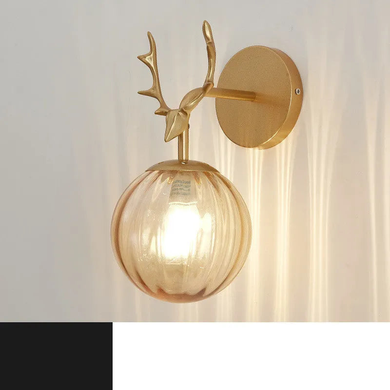 Round hand-blown glass wall lamp with golden water pattern finish mounted on a white wall, demonstrating minimalist design.