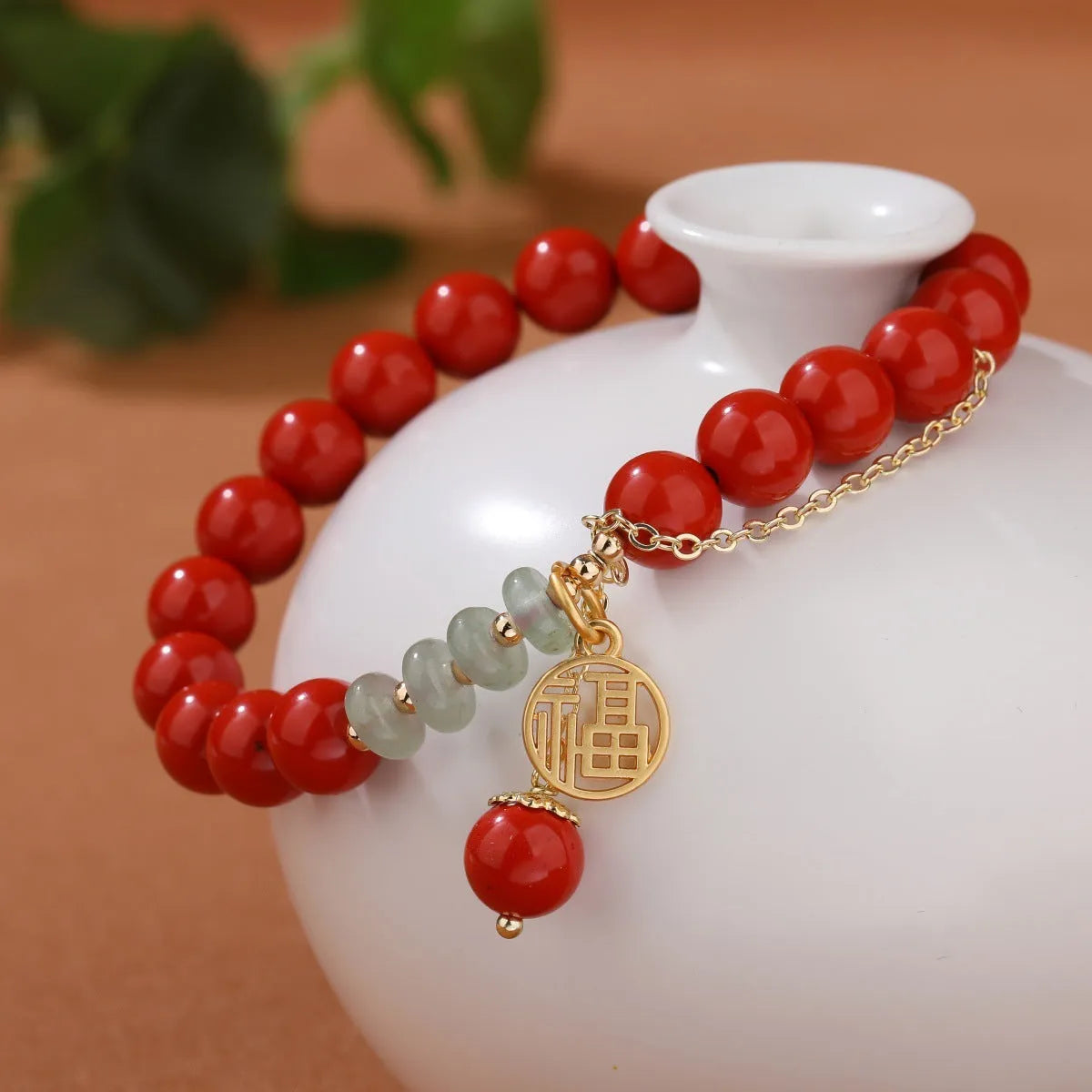 Women's handmade cinnabar bracelet with fu character charm, jade spacer beads, and red sand tassel detail