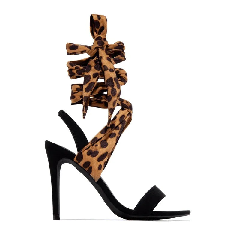 Light brown leopard print women's Roman sandals with cross-straps and a tall stiletto heel on a neutral background.