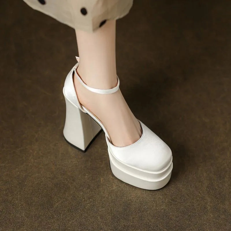 Women's white chunky heel platform pumps with a round toe and ankle strap on a plain background.