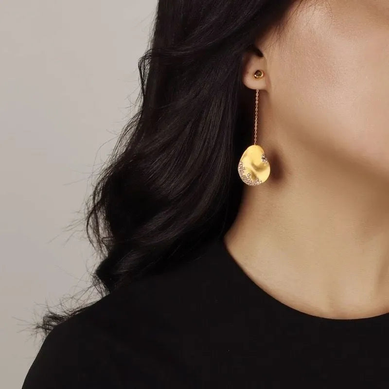 Asymmetric floral earrings with zircon stones in gold or silver finish.