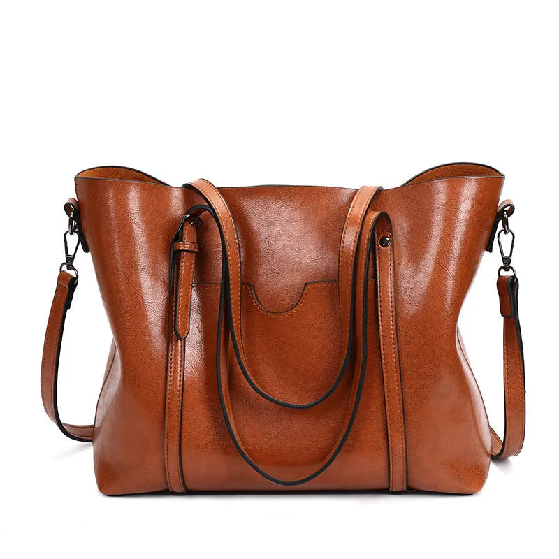 Brown retro-style women's messenger bag with top handle and shoulder strap, shown on a table.
