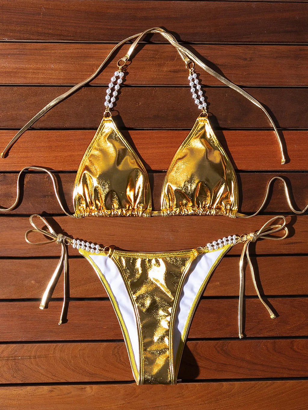 Gold women's halter lace-up bikini swimsuit with pearl chain detailing on mannequin