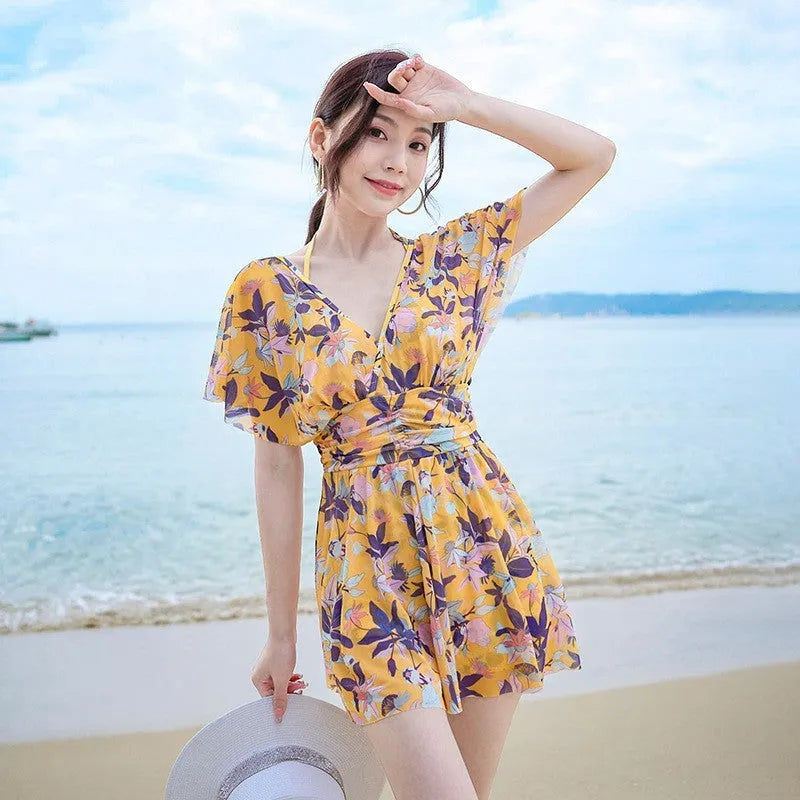 Yellow floral print women's one-piece swimsuit with skirted design on mannequin.