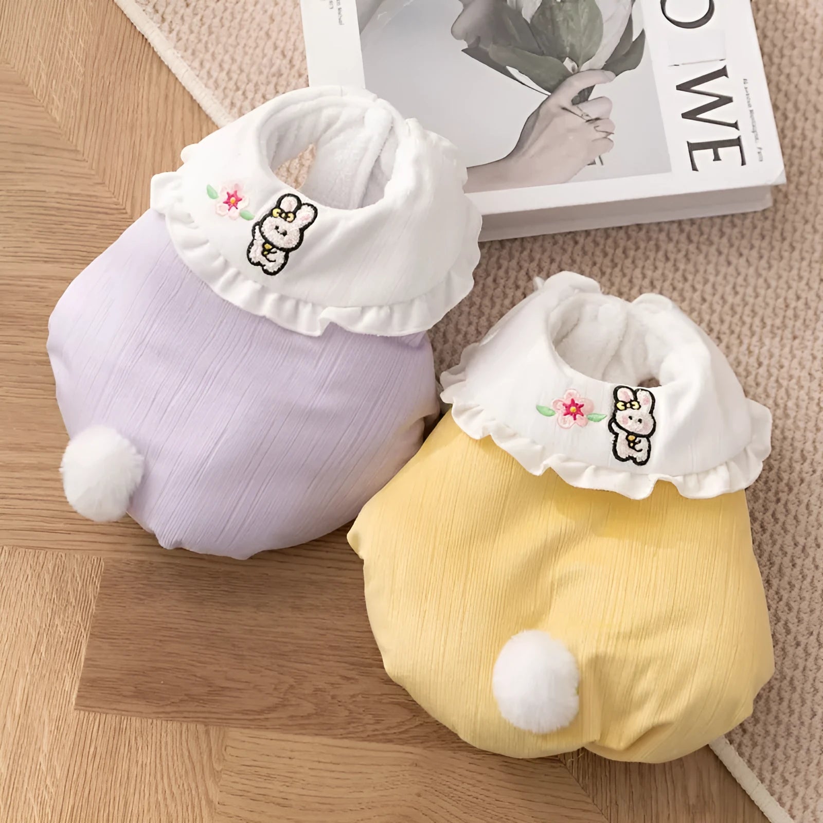 Small dog wearing a lavender bunny embroidered pet coat with white ruffled collar and fluffy pom-pom tail