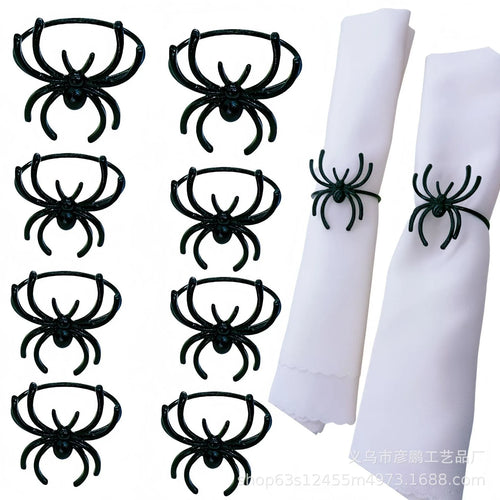 Set of six black alloy Halloween napkin rings with detailed spider design on a table setting.