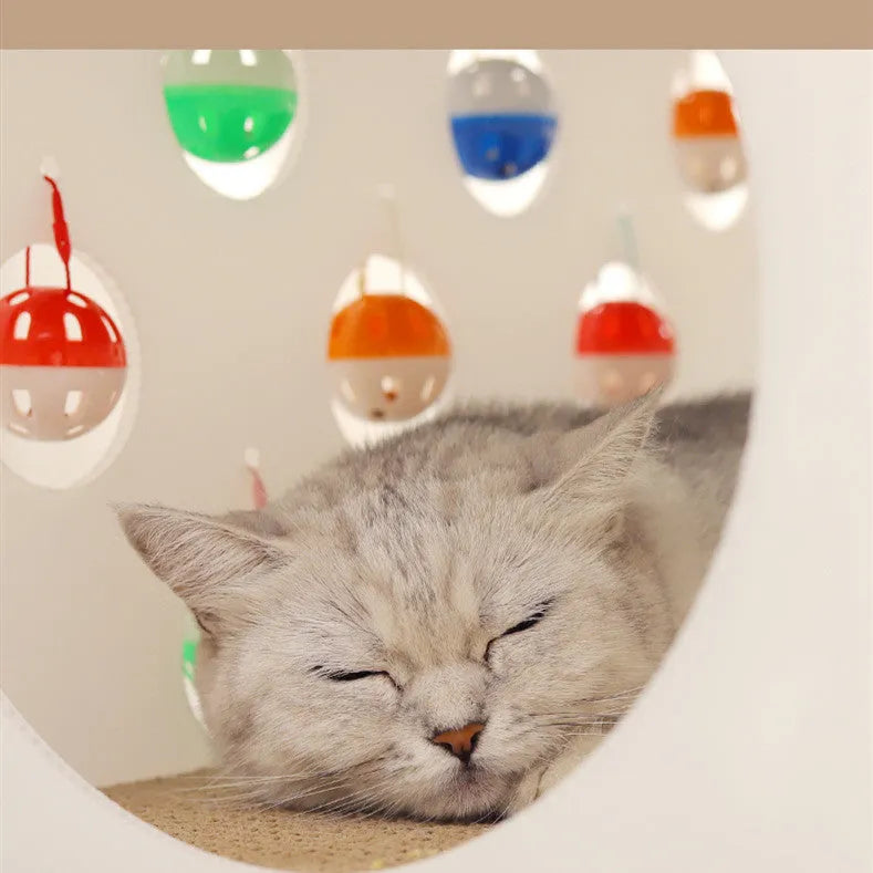 White plastic house-shaped cat scratch board with an integrated nest and a red bell ball toy inside.