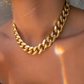 Gold-toned women's thick chain necklace with an integrated rectangular pendant, shown on a plain background.