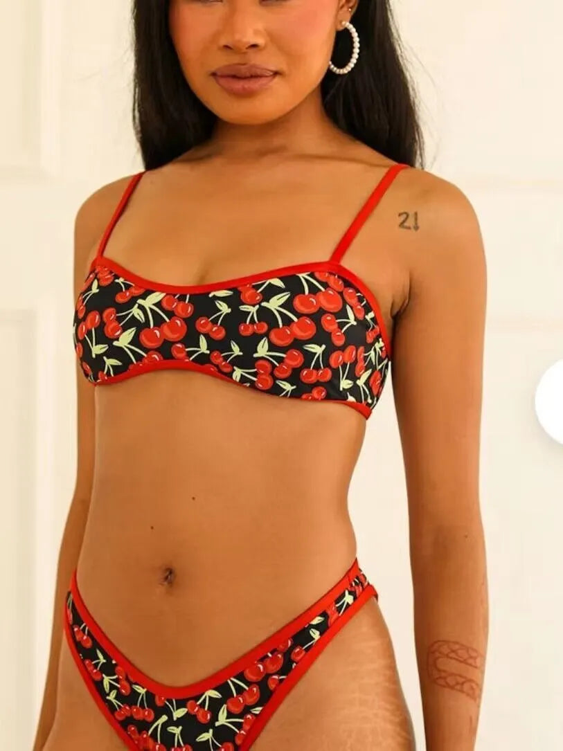 Women's cherry and floral print bikini swimsuit set with tube top and briefs on a neutral background.