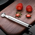 Stainless steel strawberry stem remover on a kitchen counter, modern minimalist design for coring fruit