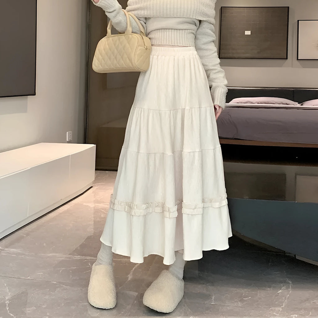A woman modelling a beige corduroy midi A-line skirt with an elasticated waistband.