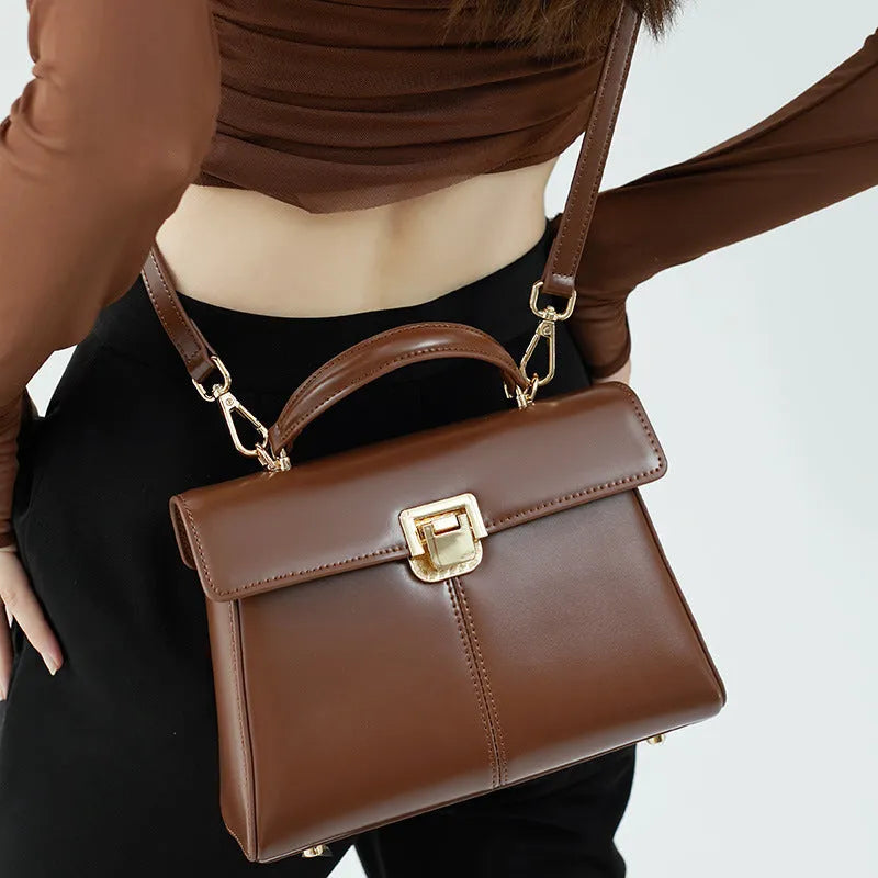 Black genuine leather women's shoulder bag with vachette clasp, showing horizontal square shape and adjustable strap.