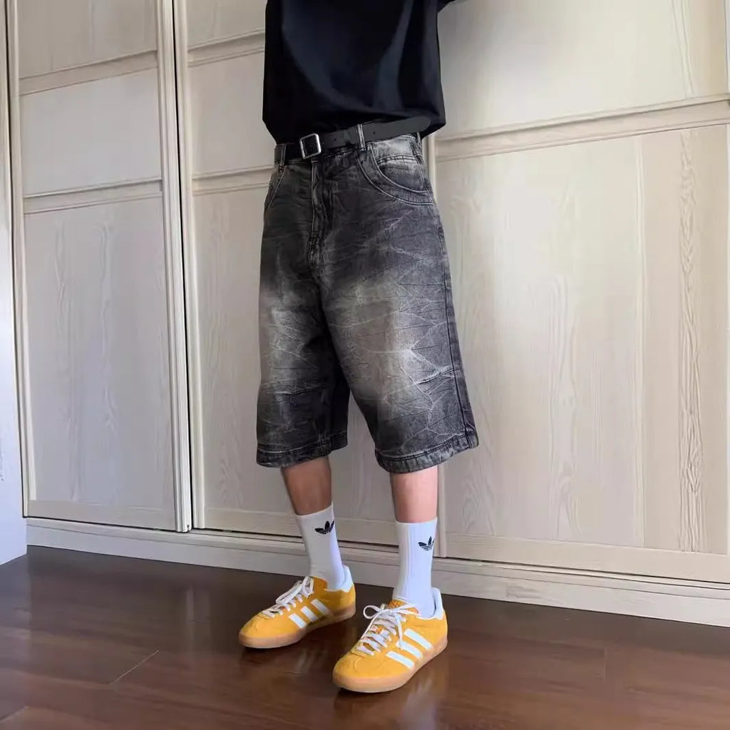 Man wearing loose-fit light blue washed denim shorts with a straight leg and cropped length.