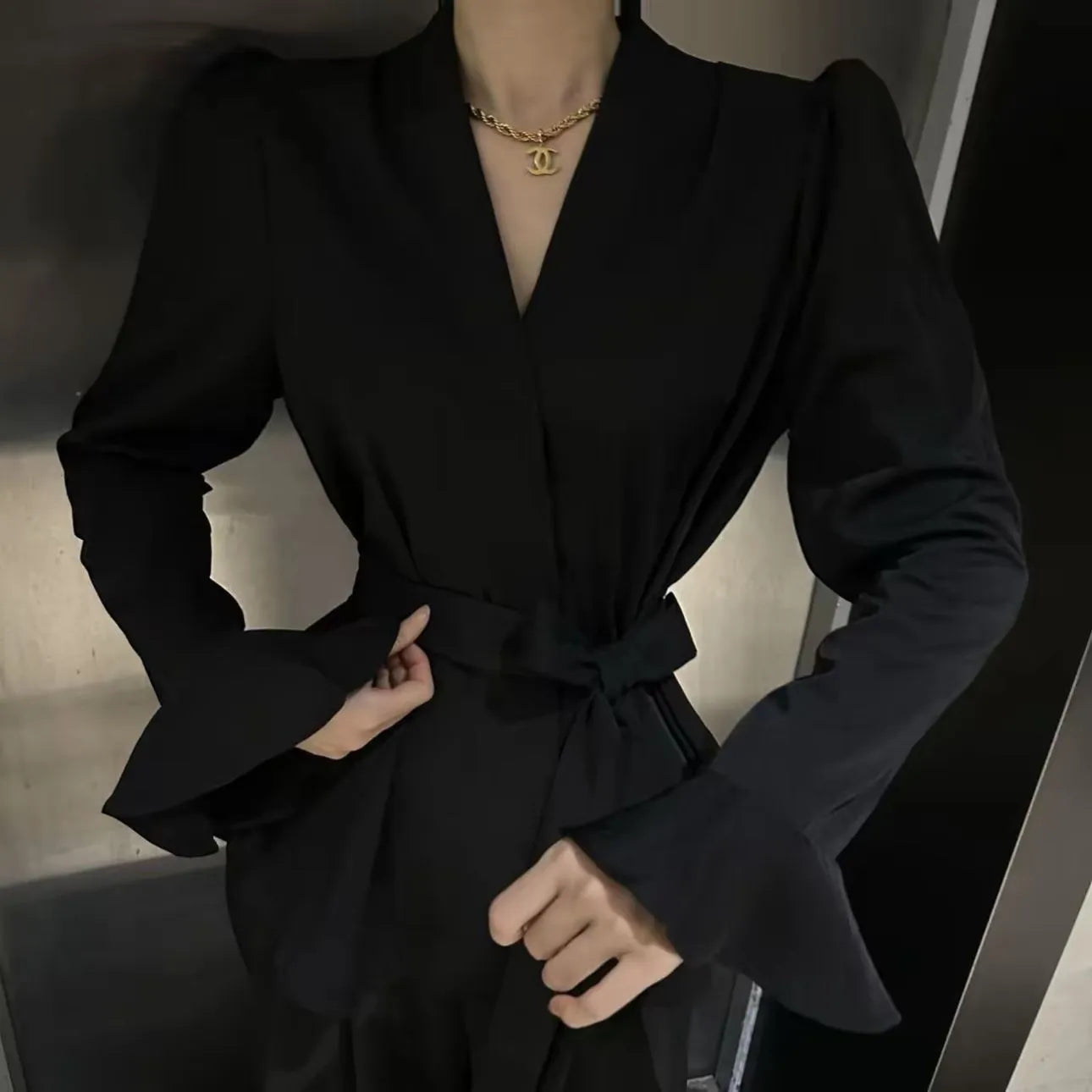 Women's black French-style long sleeve shirt with irregular collar, bell sleeves, and a tied front.