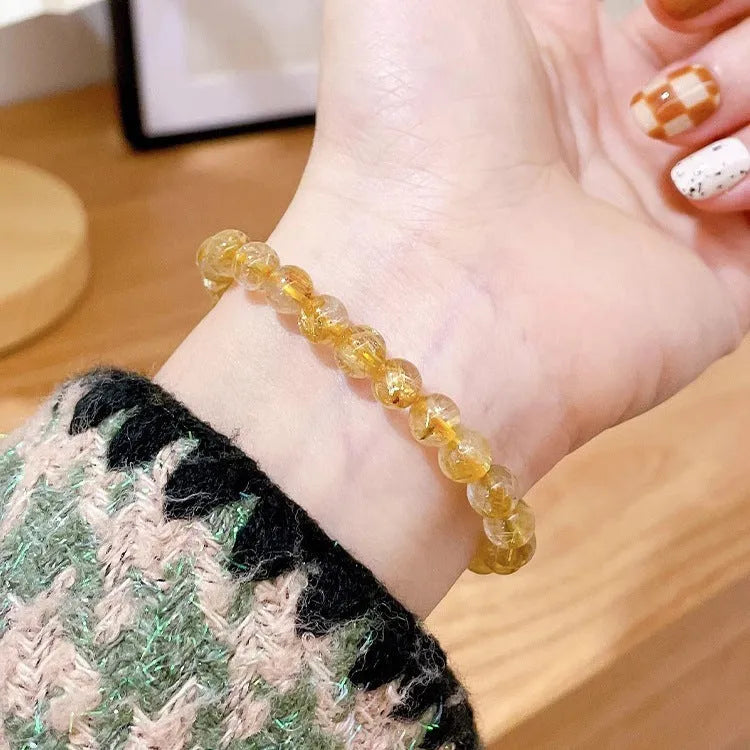 Gold rutilated quartz and sunstone bracelet with round diamond-shaped beads.