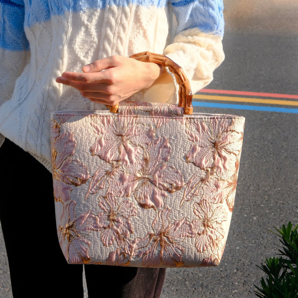Light blue canvas bag with gold bronzing flower pattern, horizontal square shape, and dual shoulder straps.