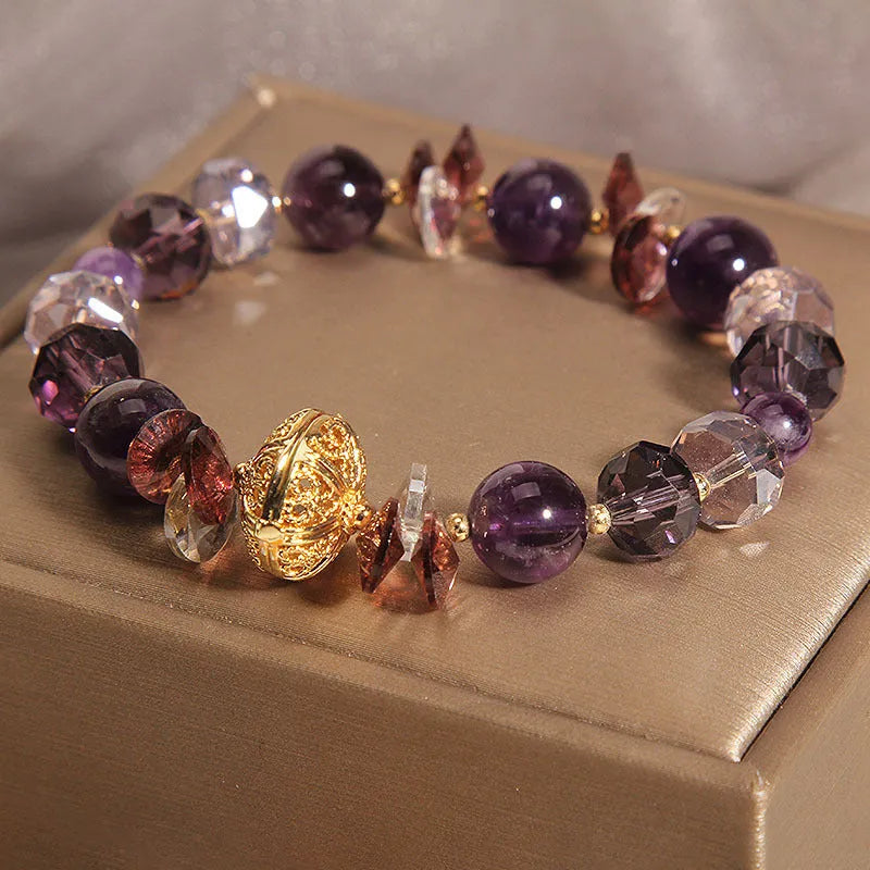 Purple crystal bracelet with pumpkin beads, wind chime charms, and rhinestone details on a wrist.