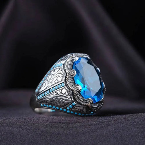 Geometric antique silver unisex ring with a central blue zircon stone on a finger.