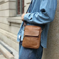 Men's brown leather crossbody shoulder bag with visible stitching and crossbody strap