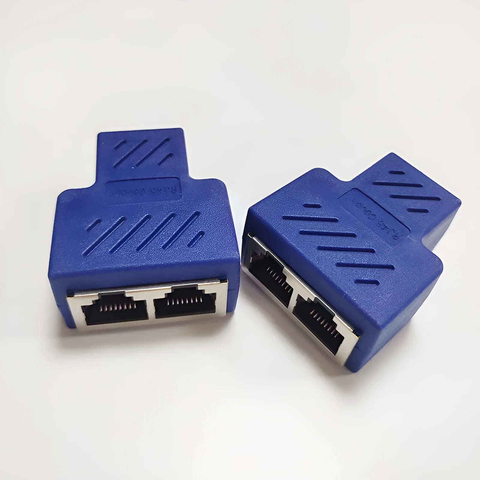 White RJ45 three-way tee network cable splitter adapter on a table.