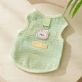 Green knitted cat clothing with a cartoon bear patch, showing hollowed-out breathable fabric.