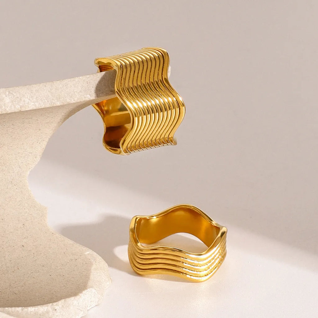 Stainless steel geometric wave ring with a wide band and electroplated finish.