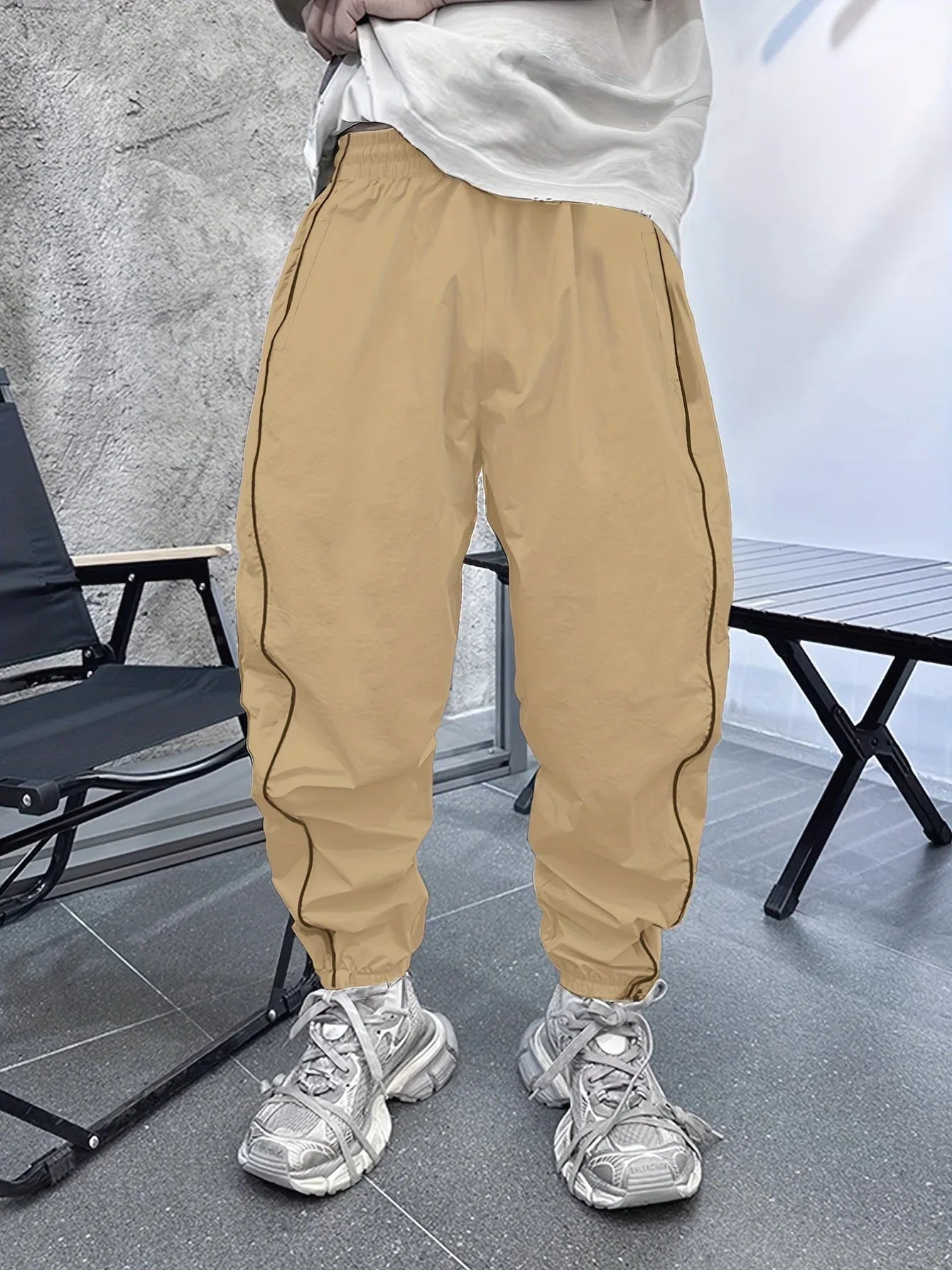 Man wearing loose-fit cropped sports trousers in bamboo fibre, showing army green colour and elastic waist.