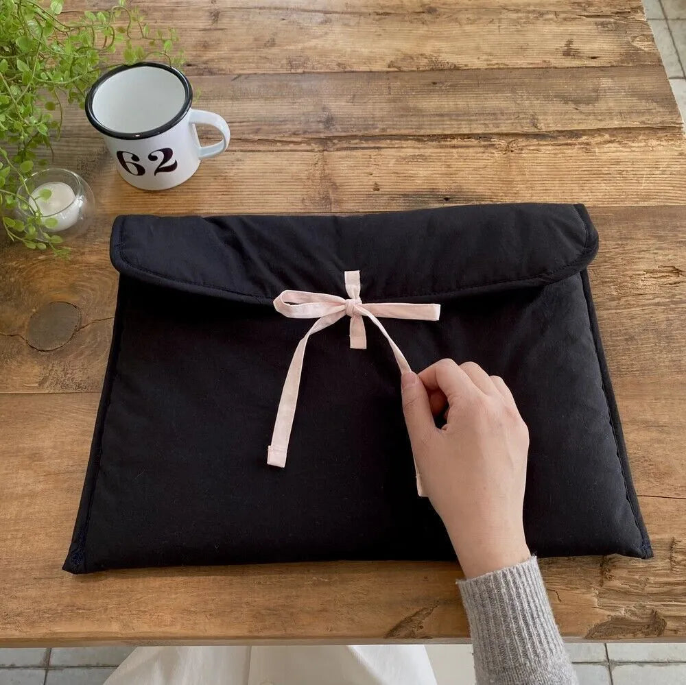 Black and white striped quilted laptop bag for women with a large decorative bow on the front.