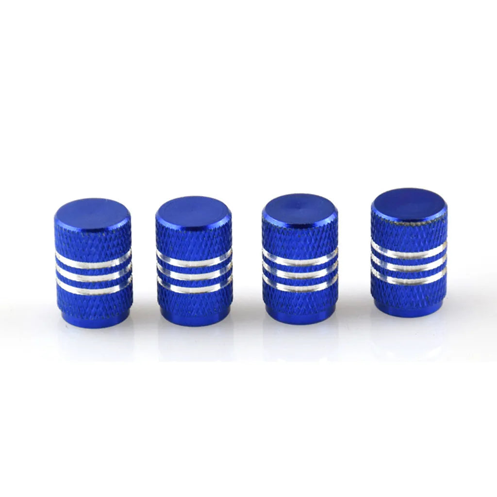 Set of coloured aluminium alloy tyre valve caps for car wheels on a grey background.