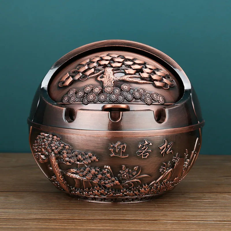 Bronze and red copper alloy decorative ashtray with smoke-extinguishing slot on a table.