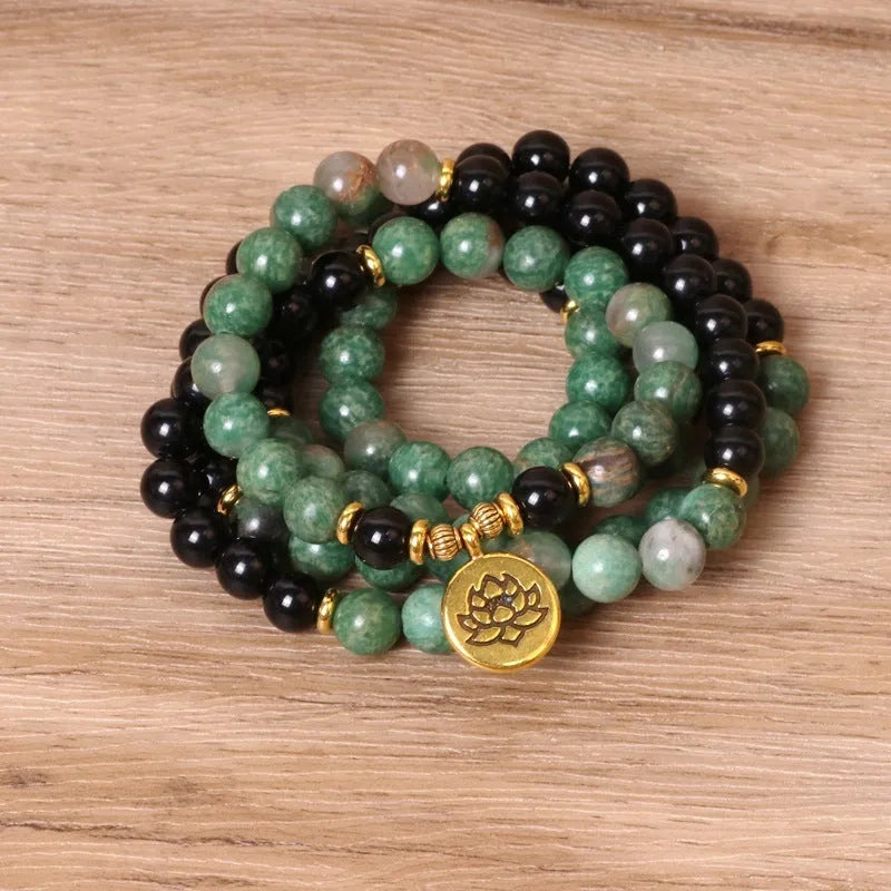 Green and black alloy bead long bracelet with elasticated band on a wrist.