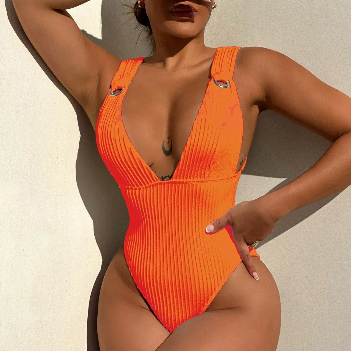 Women's solid colour one-piece swimsuit on a hanger, available in black, white, green, and orange.