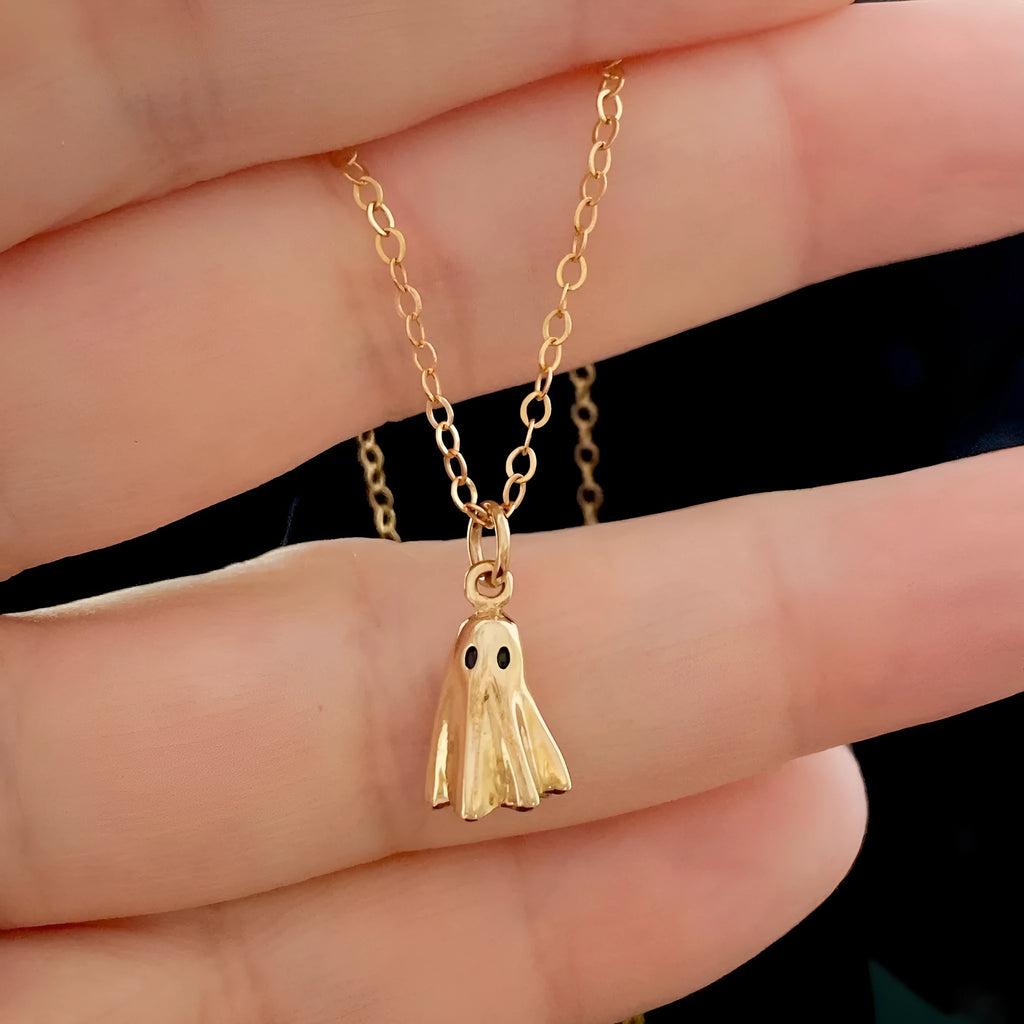 Ghost pendant necklace with twisted stainless steel chain on a person.