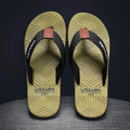 Men's black flip flops with textured non-slip sole on a beach background.