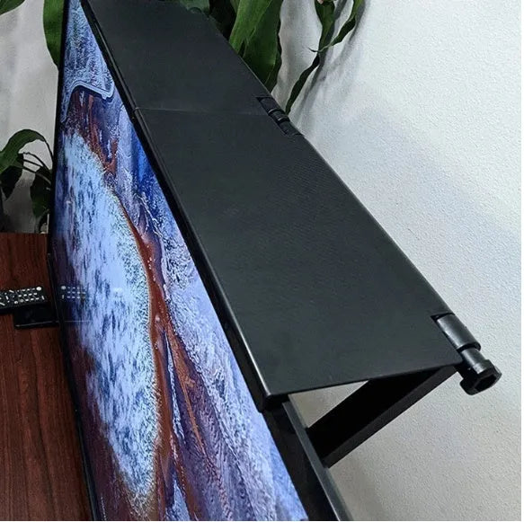 Black adjustable screen top shelf on a desktop monitor holding a streaming device and remote